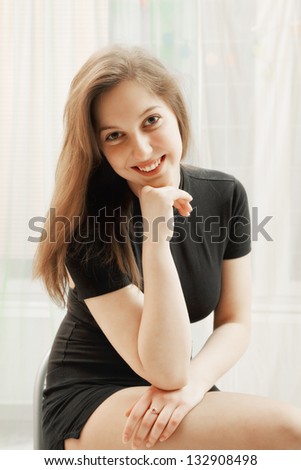 Portrait of young positive caucasian woman in black shirt sitting on the chair