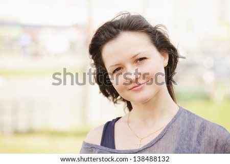 Serene young pregnant woman sitting on the grass in park looking sideways