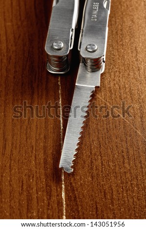 Saw blade of pocket knife over wooden surface