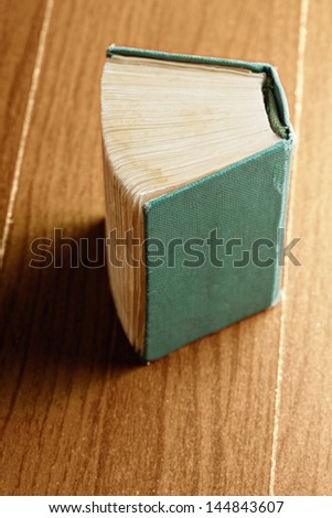 Old green book over wooden tabletop
