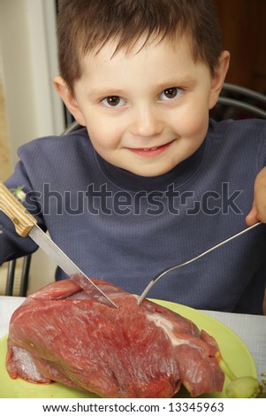Smiling boy sitting at table going to eat raw meat