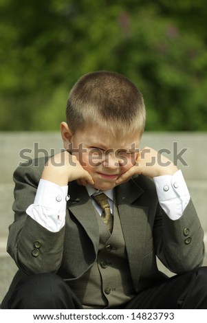 Boy in classic suit trying to look in camera while squinting