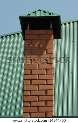 Chimney made of bricks on a green metal covered roof