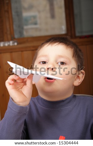 Little boy in grey jacket launching paper origami plane