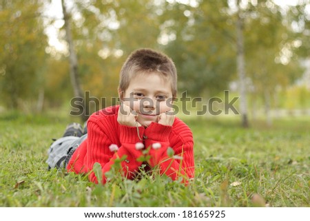 Relaxed boy in red jacket laying on grass