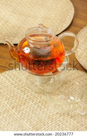 Teapot with brewing tea laying on straw mat on table
