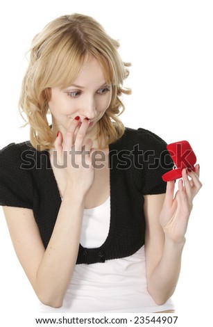 Pretty blonde young woman looking at ring in box with surprise