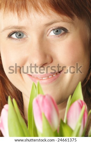 Red-haired girl face closeup with pink tulips on foreground