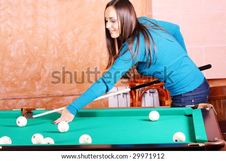 Pretty woman in blue jumper playing billiards