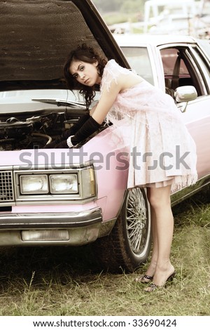 Serious young woman in pink repairing retro car