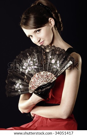 Young woman and fan over dark background