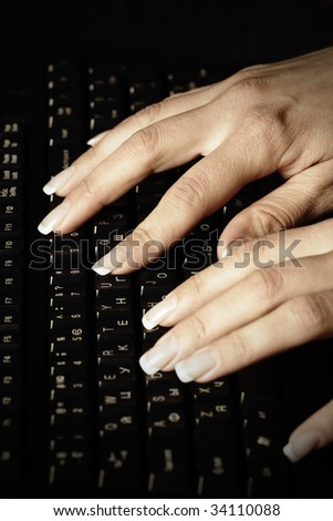 Woman manicured hands typing on black keyboard