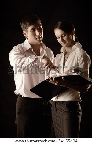 Man giving instructions to young woman holding folder