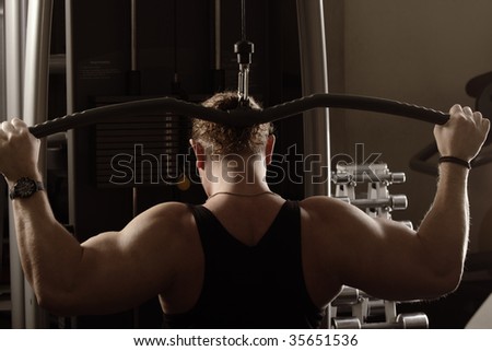 Strong guy training back muscles using equipment