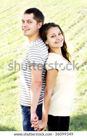 Pretty couple standing back to back outdoor photo