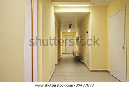 Empty corridor with yellow walls with hair-driers at the end