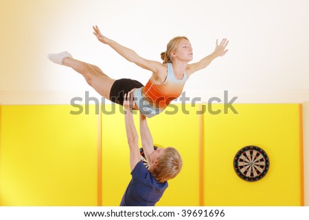 Young couple training acrobatic feat in gym