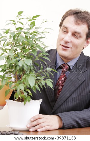 Smiling businessman in formal wear watering plant