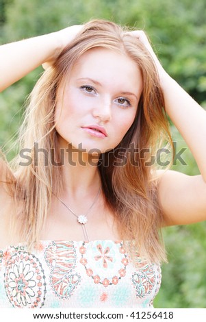 Young fairhaired woman raising hands over head outdoors
