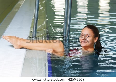 Young smiling woman in water put legs on pool edge
