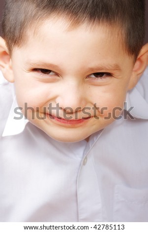 Little Smiling boy in white shirt inclining head forward