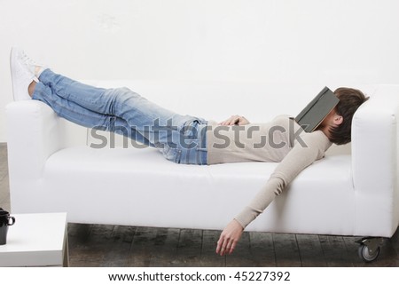 Young woman having afternoon nap with book on face