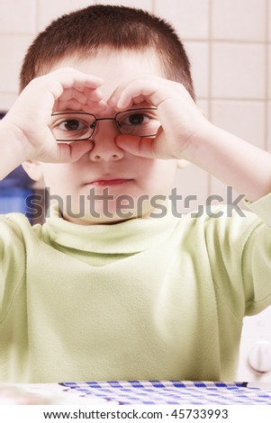 Little boy in eyeglasses holding hands like binoculars