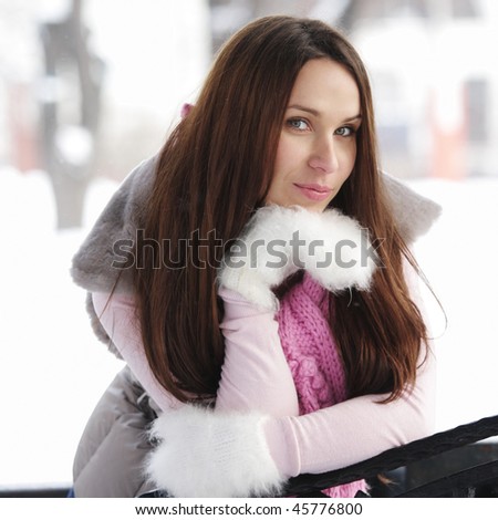 Pretty young brunette woman wearing white downy mittens in winter day