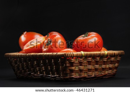 Basket with ripe red tomatoes against dark background