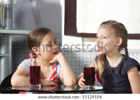Two little girls sitting at in cafe with cherry juice selective focus
