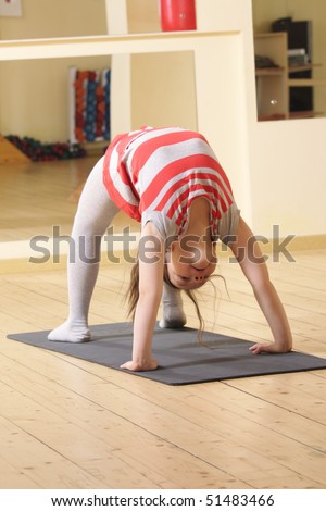 Little gymnast girl in bridge stand on gray mat
