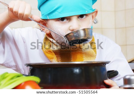 Little cook in green cap testing food from ladle