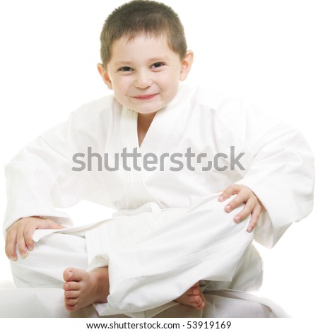 Little karate kid sitting legs crossed against white background