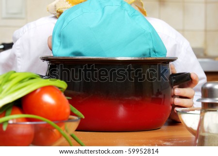 Little cook put head in pan at kitchen closeup photo