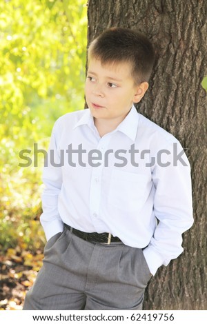 Boy in formal wear standing at tree keeping hands in pockets