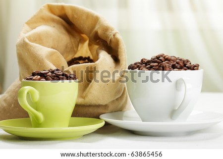 Same roasted coffee beans in different cups side-view