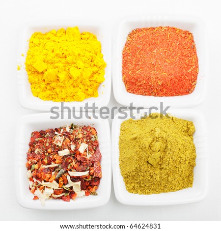 Various spices in white dishes on tablecloth above view