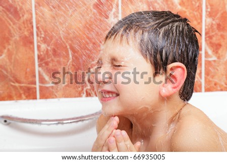 Little boy in bath under water flushing from shower