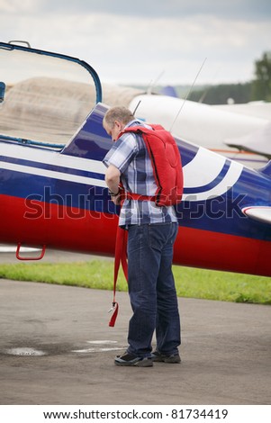 Pilot getting on parachute at light aircraft