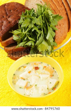Cheese soup and bread with greens on yellow cloth