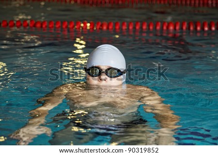 Boy in swimming pool with blue cap and goggles