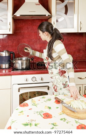 Brunette checking pan while cooking in kitchen