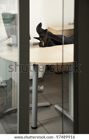 Woman legs on desk through office door