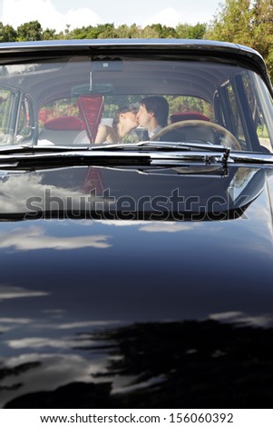 Car with kissing bride and groom on the rear seat