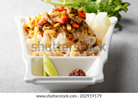 Ashlampho cold snack made of rice noodles and served with greens, lime and vegetables