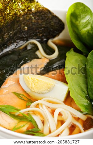 Fish ramen soup served with noodles, salmon, greens and egg closeup photo