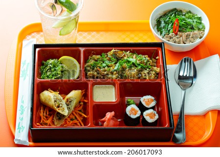 Combo lunch box with various food over the orange tabletop