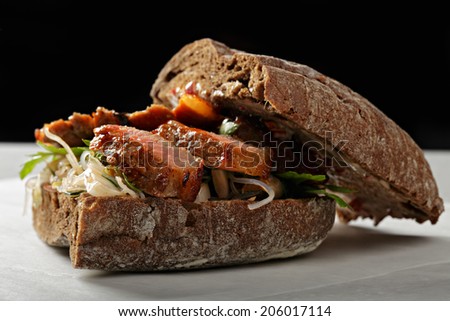 Beef sandwich on a rye bread stuffed with kimchi cabbage closeup photo against dark background