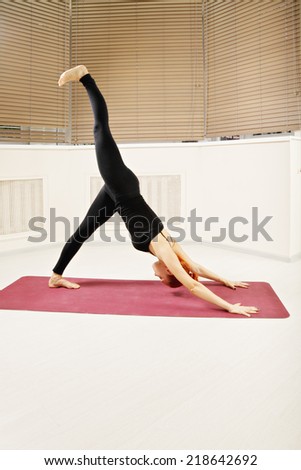 Redhead exercising downward facing dog yoga pose leg raised