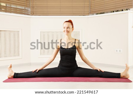 Contented redhead stretching legs out yoga pose